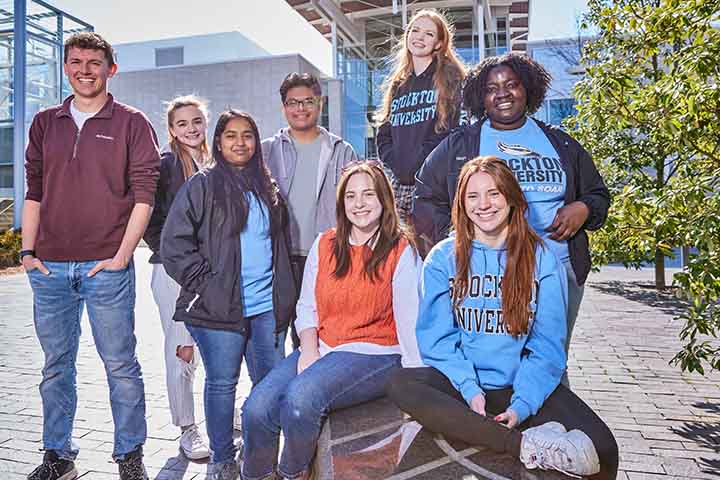 A diverse group of students pose outside of the Campus Center