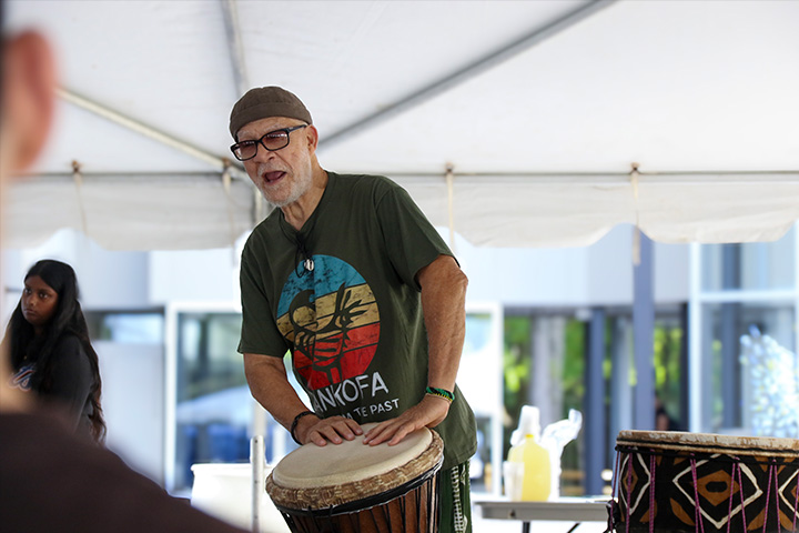 An older gentleman plays a bongo drum