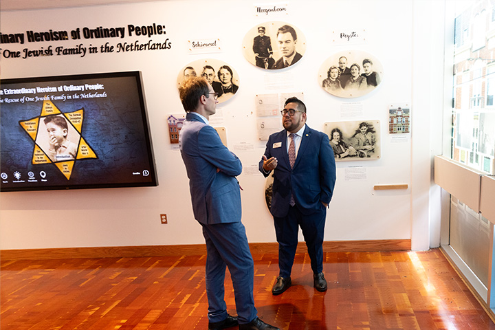 Two men in suits chat in an exhibit in the Holocaust Resource Center