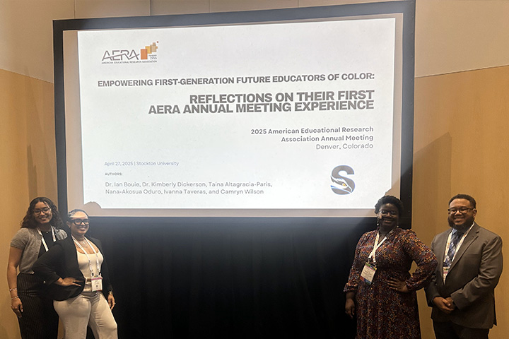 Three Stockton students and a faculty member pose in front of their poster presentation at a conference