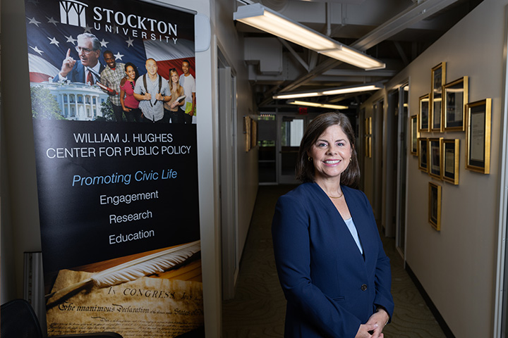 Tina Zappile poses next to a banner for the William J. Hughes Center for Public Policy
