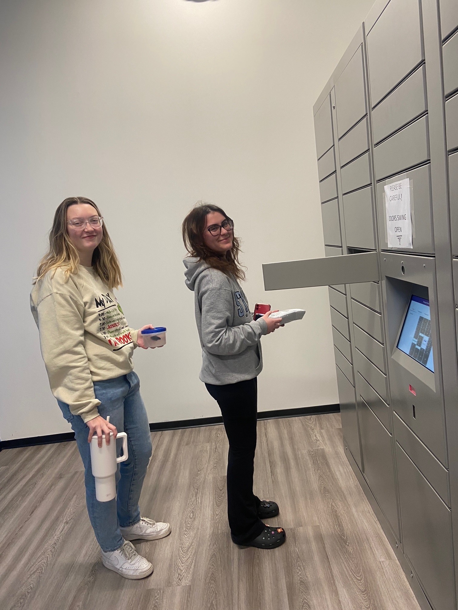 Two students opening up the package lockers