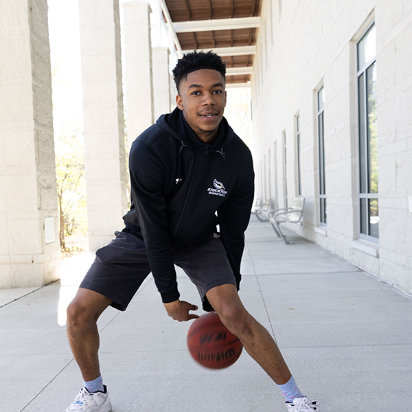 Kyion Flanders, dribbling a basketball outside of the Campus Center