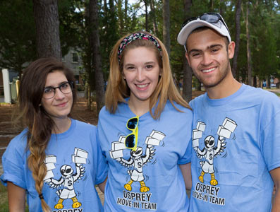 Three students smiling at the camera wearing blue Stockton Opsreys shirts.