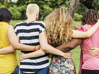 A group of women standing outside, with their arms around each other in a hug.