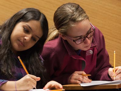 two students writing in notebooks.