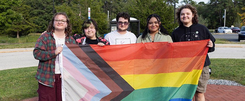 Student speakers holding LGBTQ Flag before raising it 