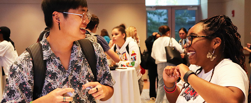 Two students laughing at a cocktail table