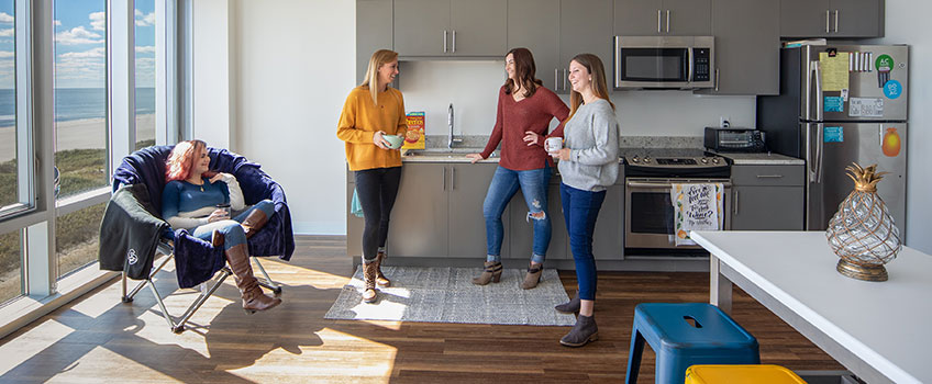 Four students in the kitchen of a residential apartment.