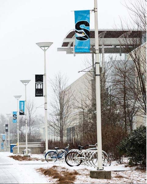 snow coming down outside of campus center with bicycles