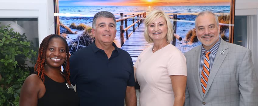 two women, two men smiling in front of painting 