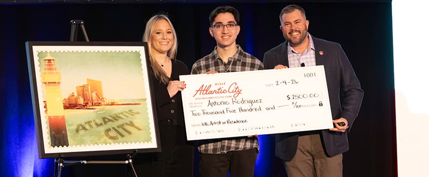 student holding scholarship check with man to right and woman at left