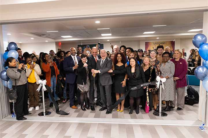A crowd of faculty, staff and students behind a ribbon that has just been cut.