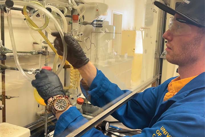 Trey Basher in blue lab coat conducting research