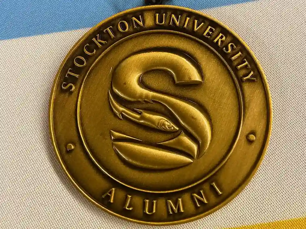 Close-up of a Stockton University Alumni medallion featuring the Osprey logo.